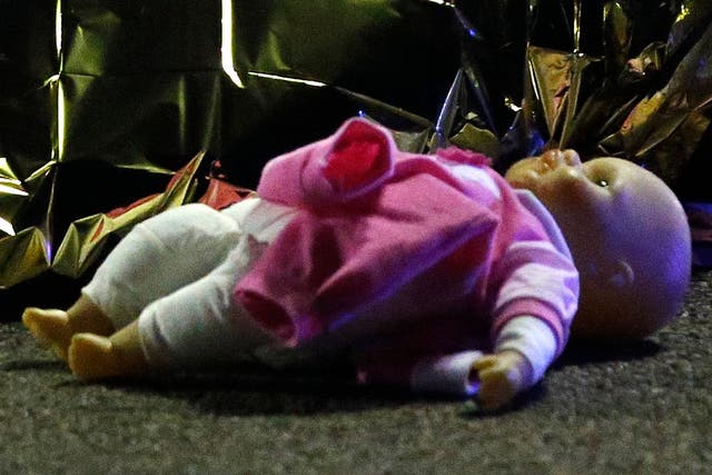 A doll lies next to the covered body of a girl killed when a lorry plunged into a crowd in Nice