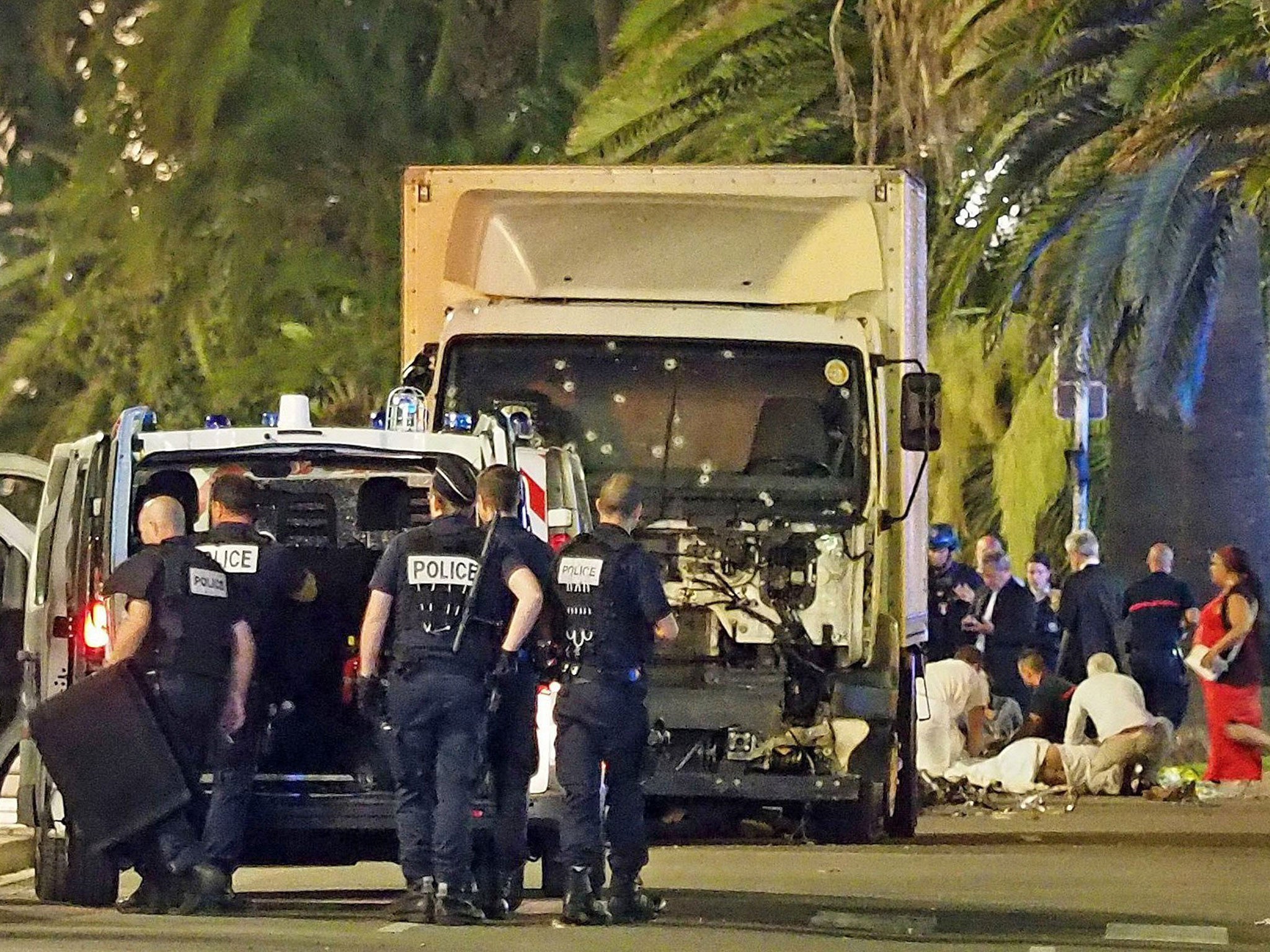 Police stand by as medical personnel attend a person on the ground, right, in the early hours of Friday