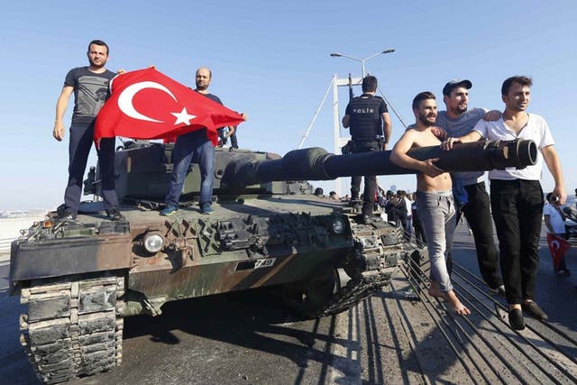 Civilians carry the Turkish flag onto a tank abandoned by rebel soldiers 