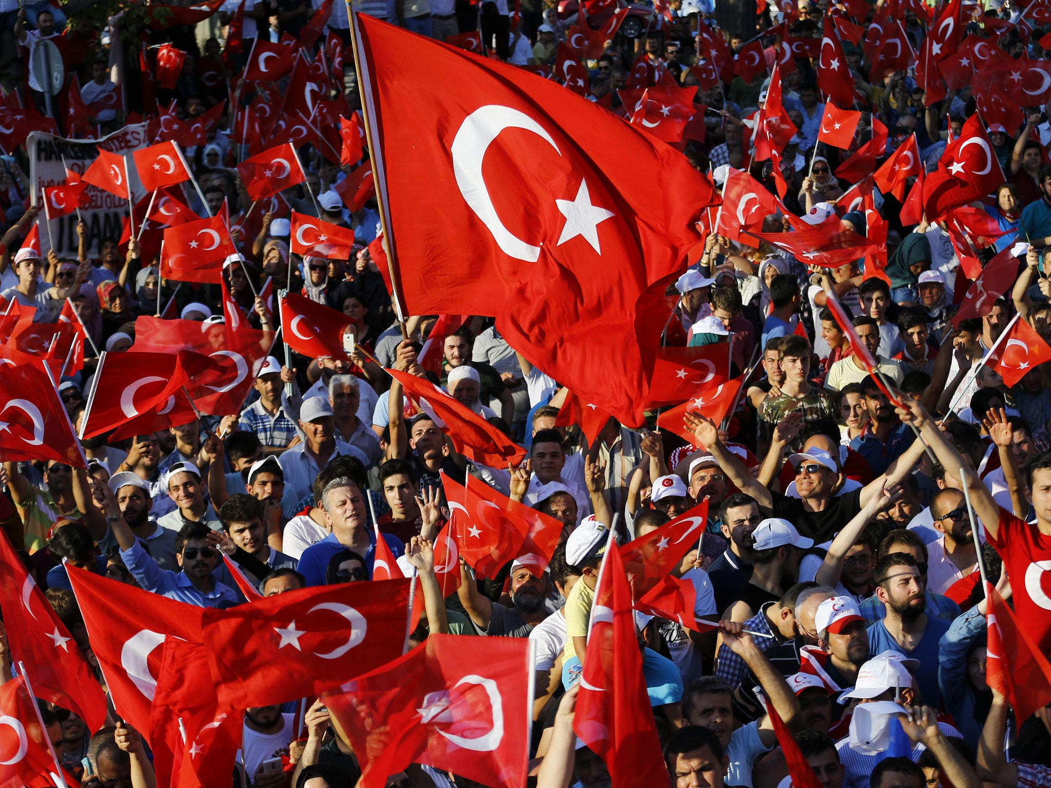 People wave flags as they wait for Turkish President Recep Tayyip Erdogan to appear for a speech in Istanbul on 16 July