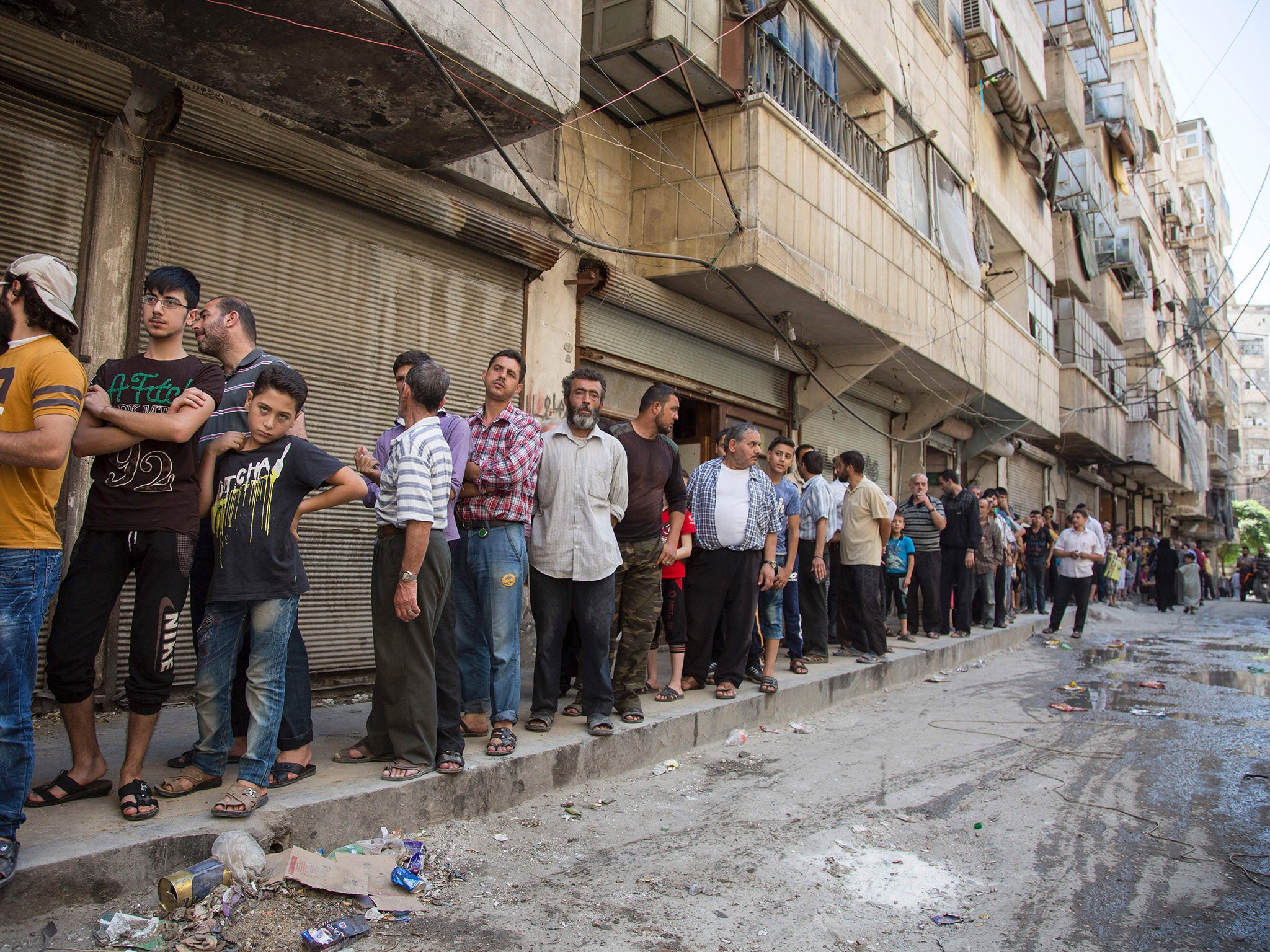 Syrians queue up to buy bread in a rebel held area of Aleppo on 12 July 016