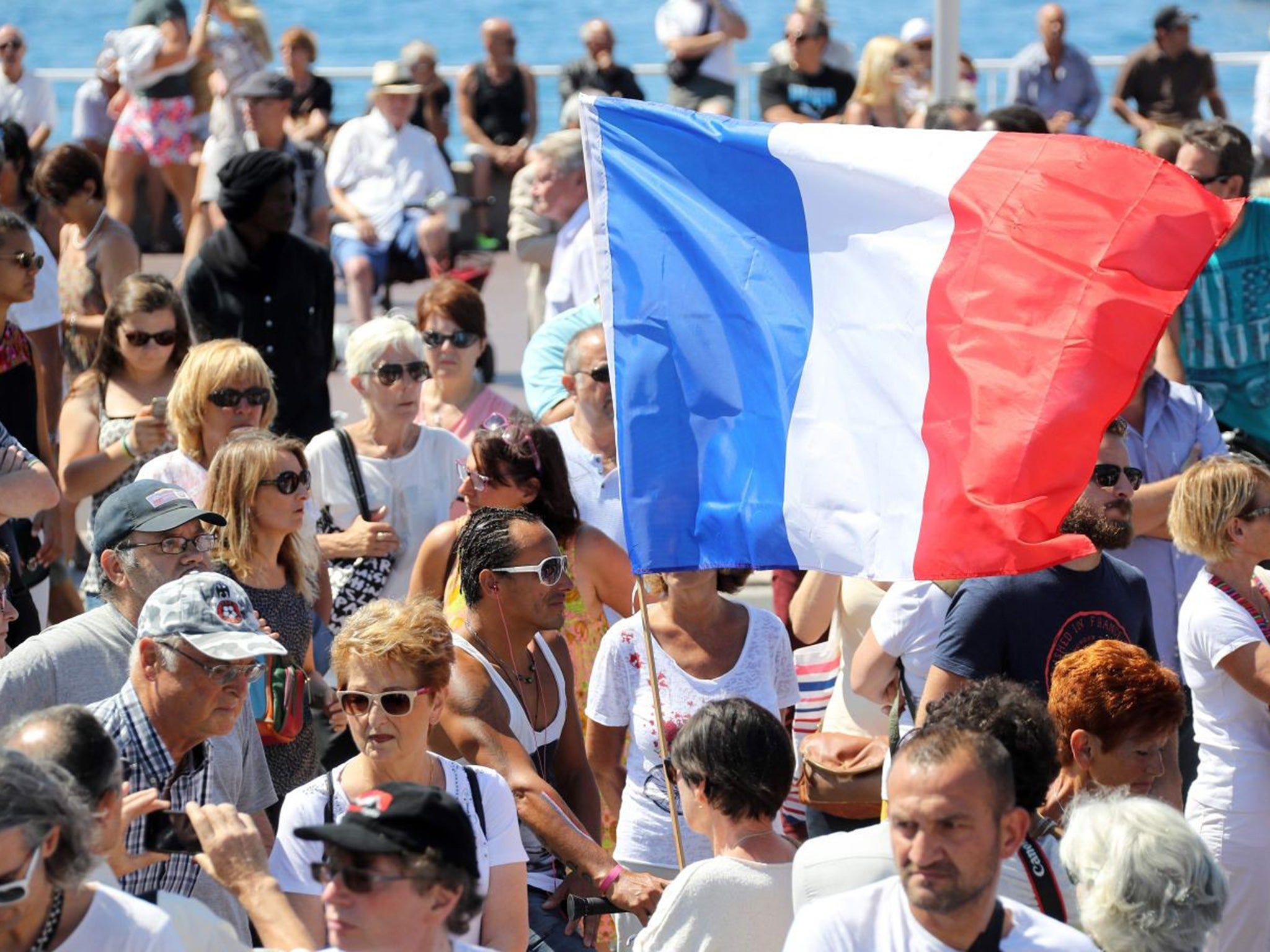A man holds a French flag at a memorial service for the victims of the Nice terror attack. The crowds cheered and raised their fists in the air as they heard their national anthem but booed their prime minister