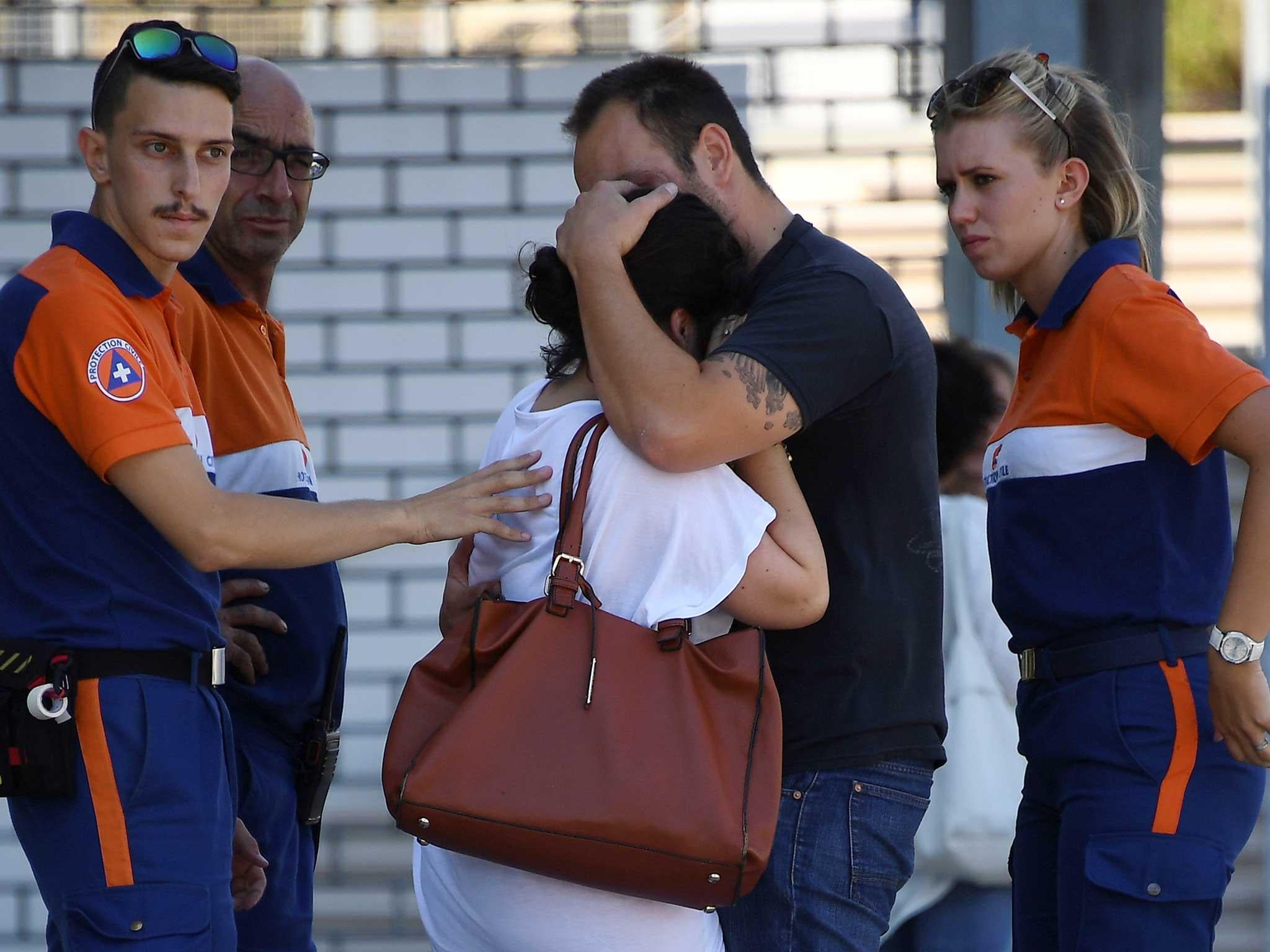 Protection civil agents stand around people hugging each other outside Pasteur hospital in the French riviera town of Nice
