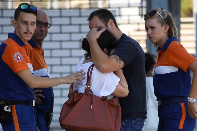 Protection civil agents stand around people hugging each other outside Pasteur hospital in the French riviera town of Nice
