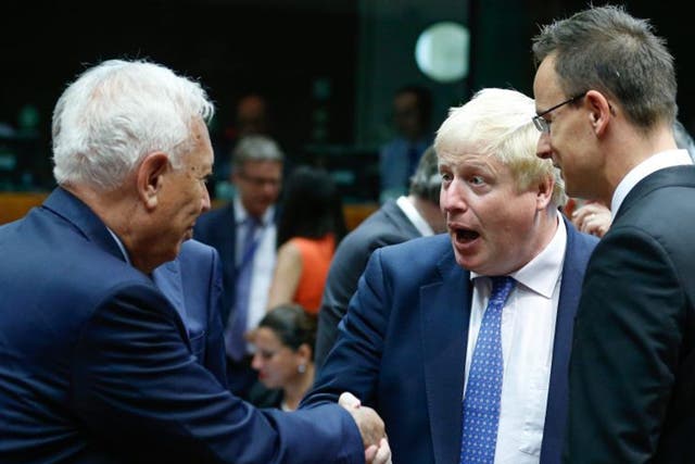 Britain's Foreign Secretary Boris Johnson (C) and Spanish Foreign Minister Jose Manuel Garcia-Margallo (L) shake hands during an EU Foreign Affairs Council meeting