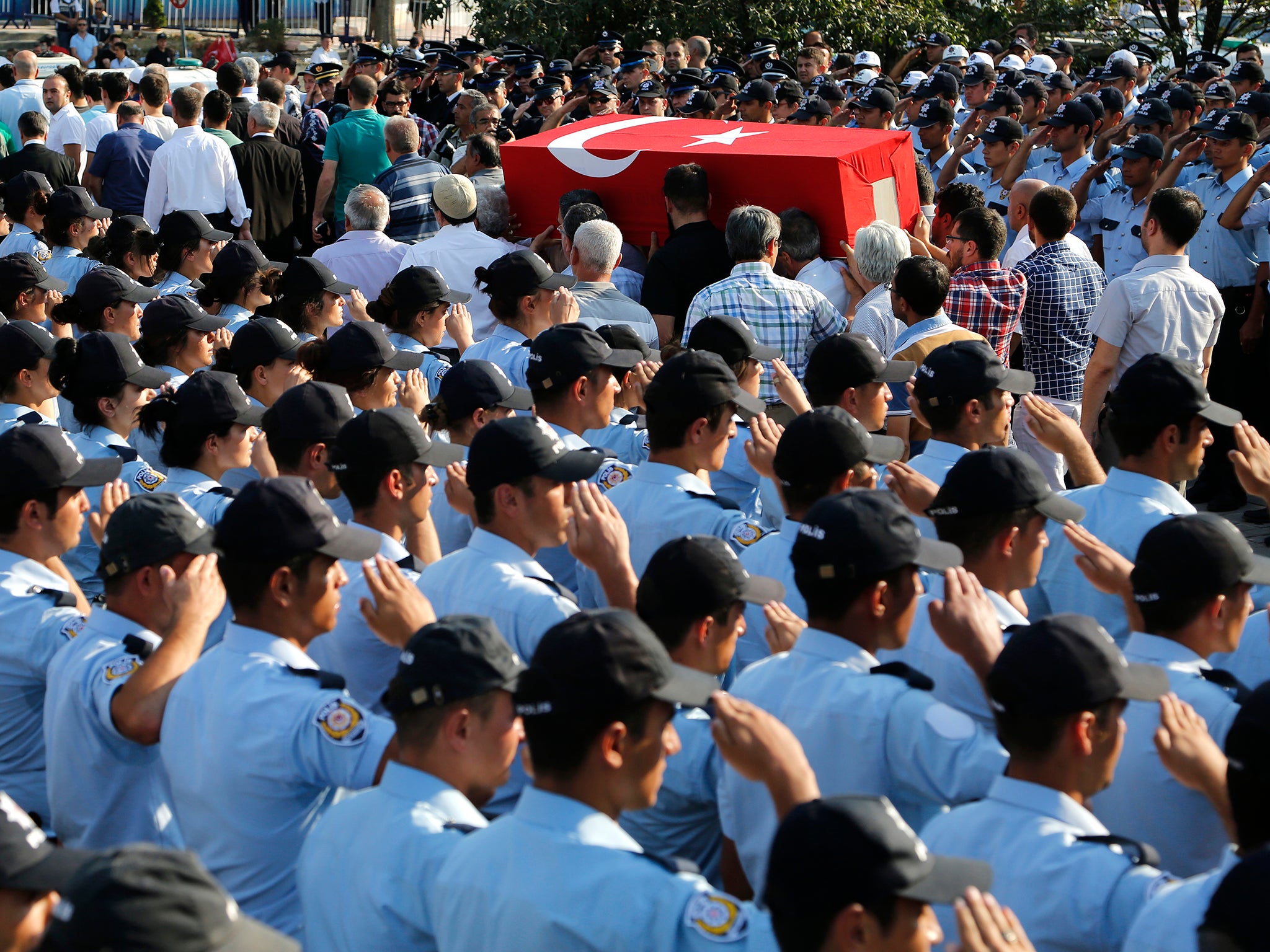 Turkish police salute as mourners carry the coffin of a police officer killed on Friday during the failed military coup