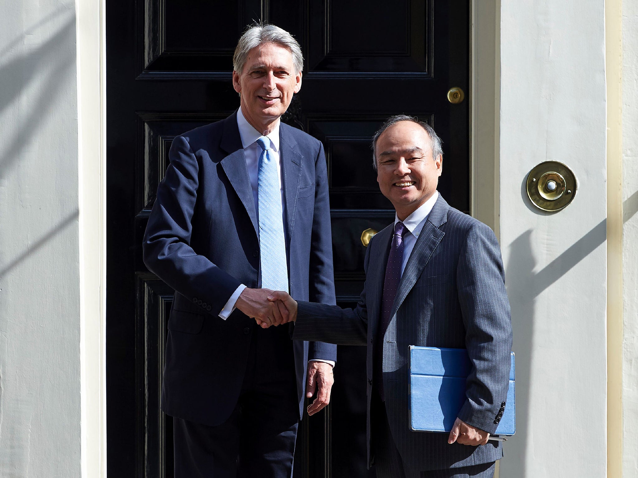 British Finance Minister Philip Hammond (L) greets Masayoshi Son, CEO of Japanese mobile giant SoftBank, the company that has agreed a takeover of ARM