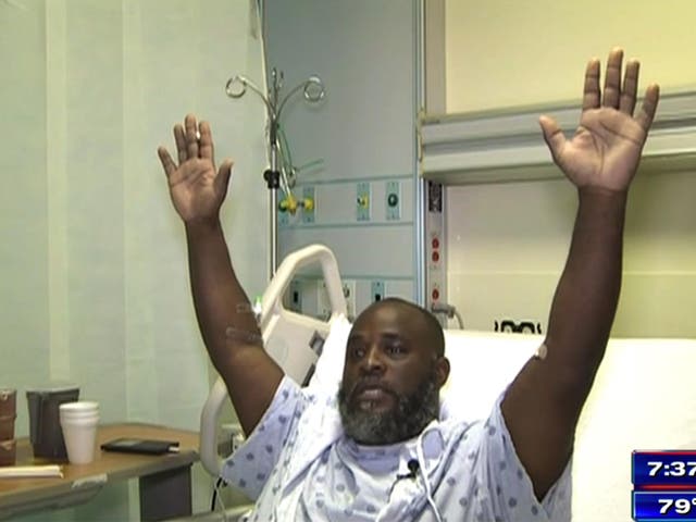 Charles Kinsey demonstrates how his hands were positioned in the moments before he was shot. He is now recovering in hospital