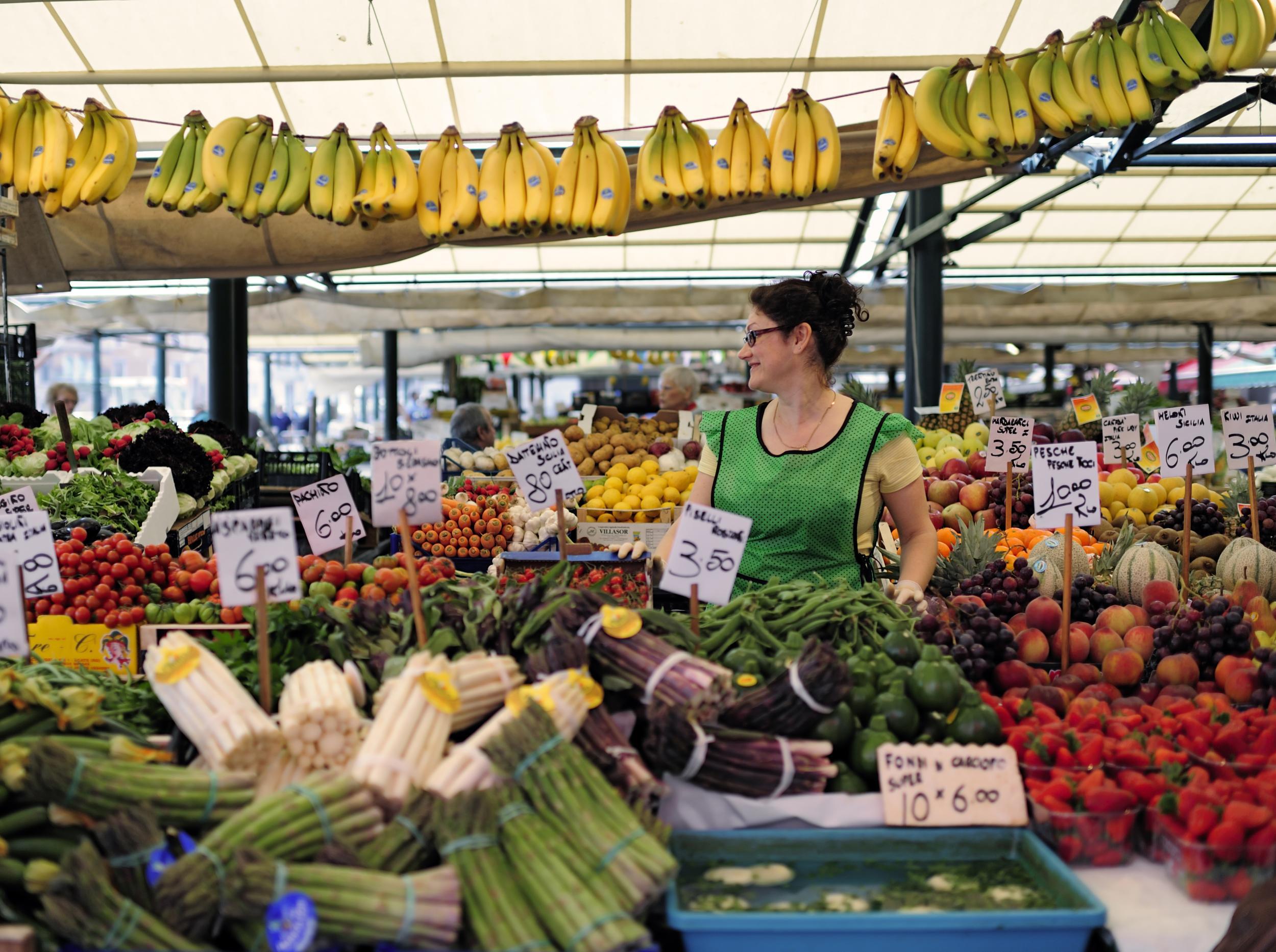 A woman sells fruit and vegetables at a market in Italy