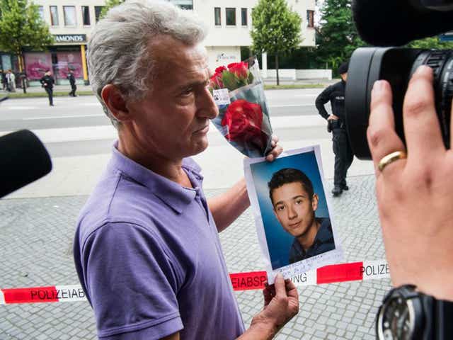 The father of one of the Munich victims holds up a picture of his son