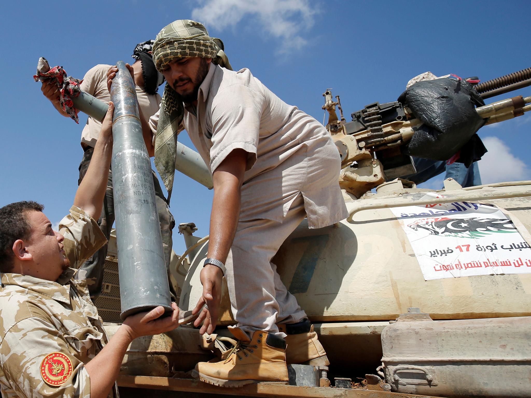 &#13;
Fighters carry a tank shell during a battle with Isis in Sirte &#13;