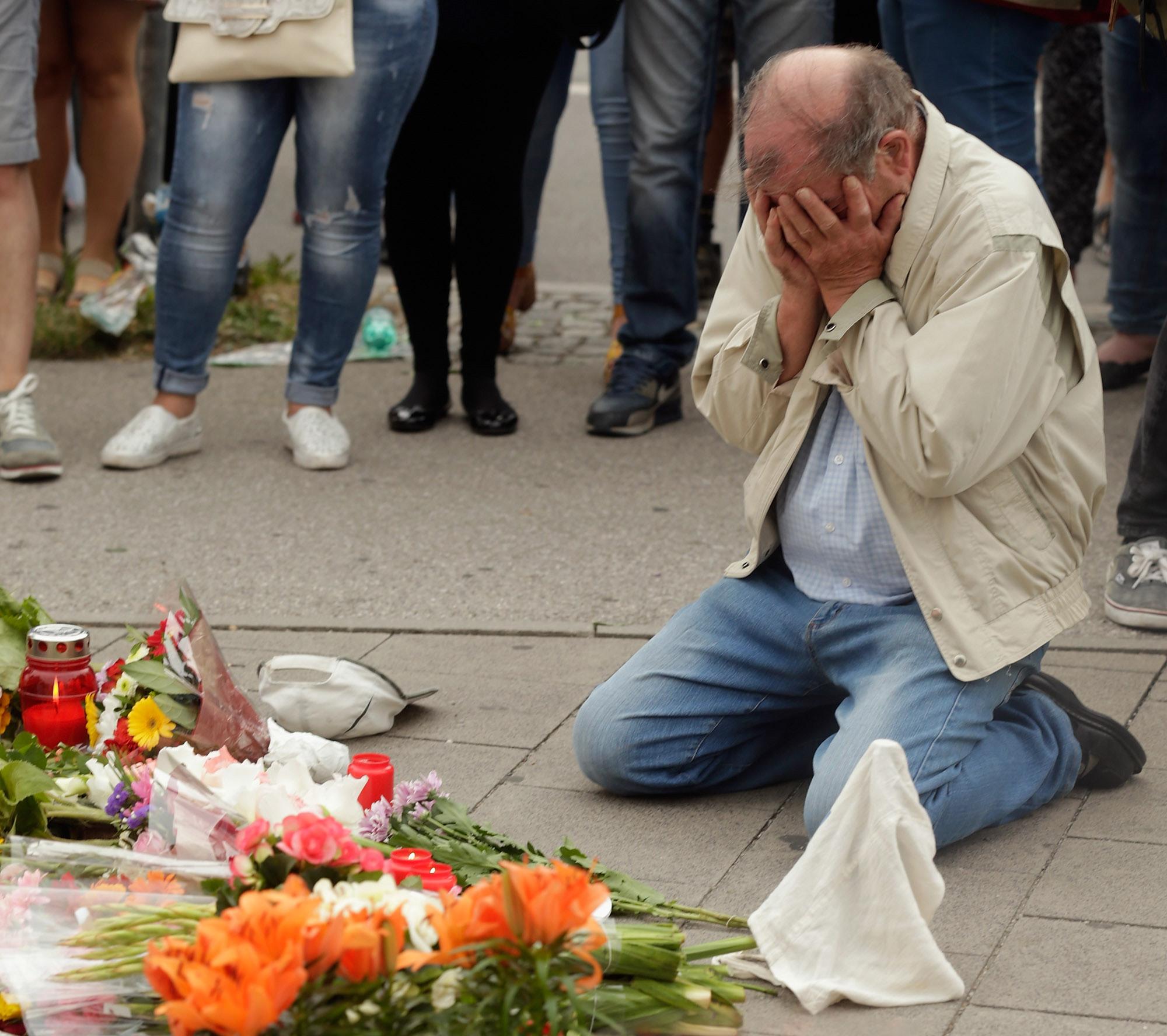 People mourn near the crime scene at OEZ shopping center the day after a shooting spree left nine victims dead in Munich, Germany