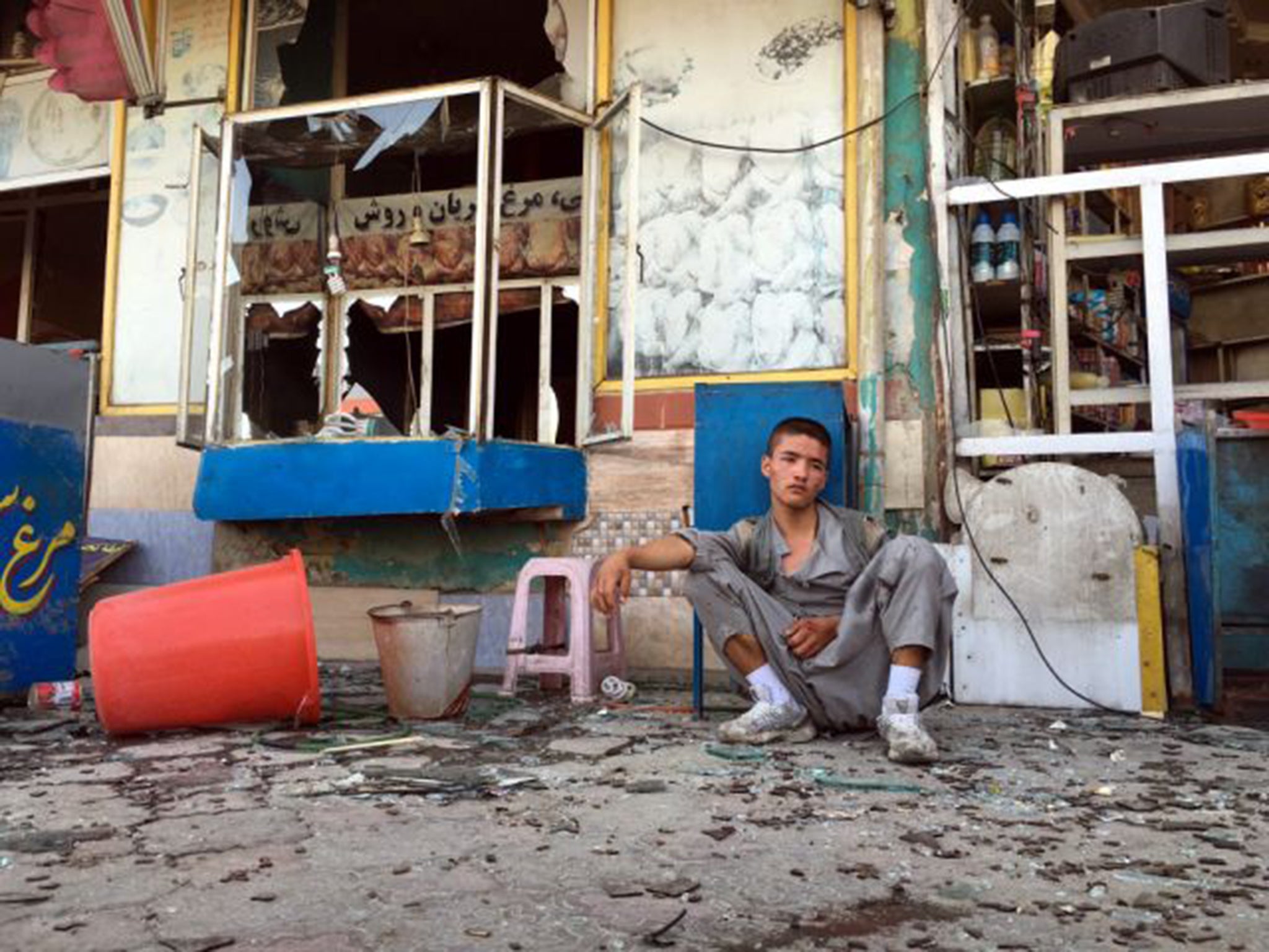 A young man sits among the wreckage after a suicide bomb attack in Kabul in July