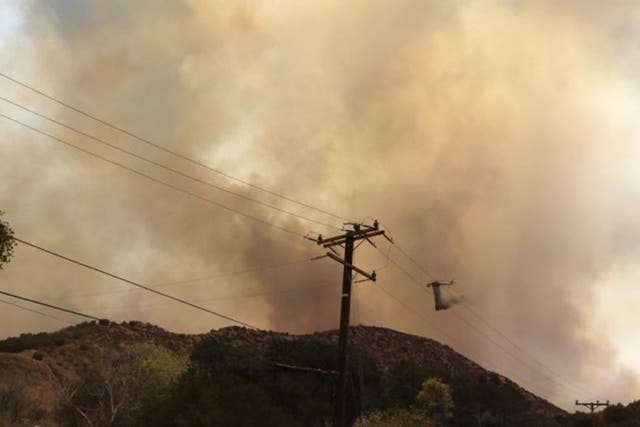 A helicopter drops water on a wildfire burning in Santa Clarita, California