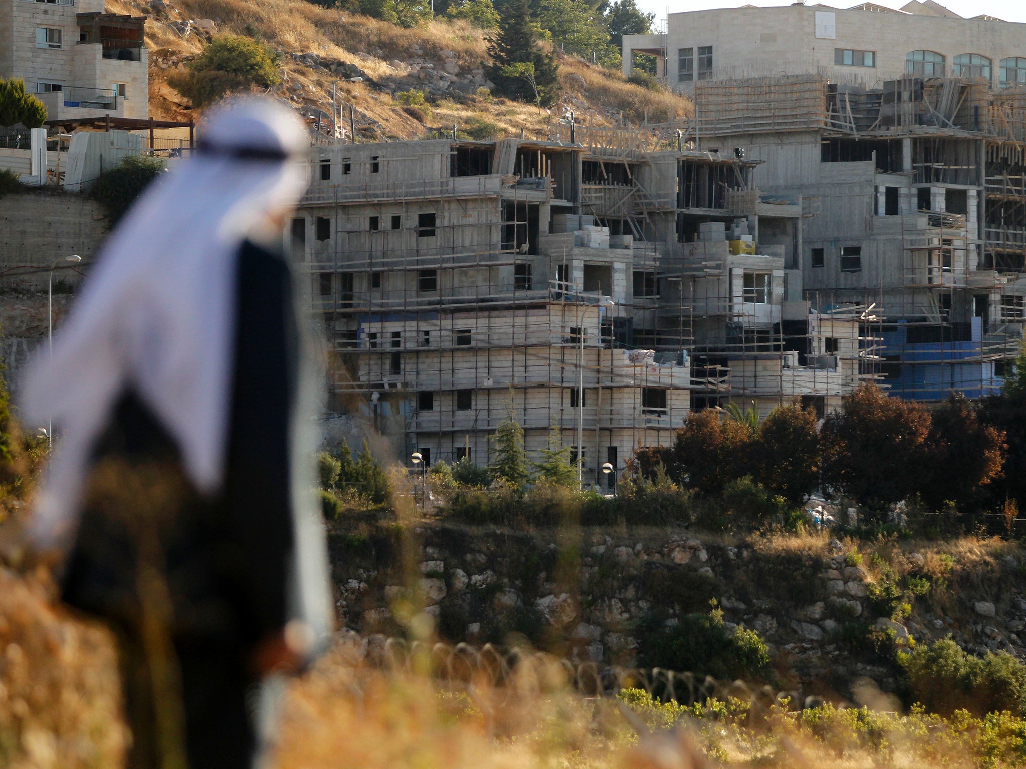 A Palestinian man in front of the Kiryat Arba settlement on the outskirts of Hebron