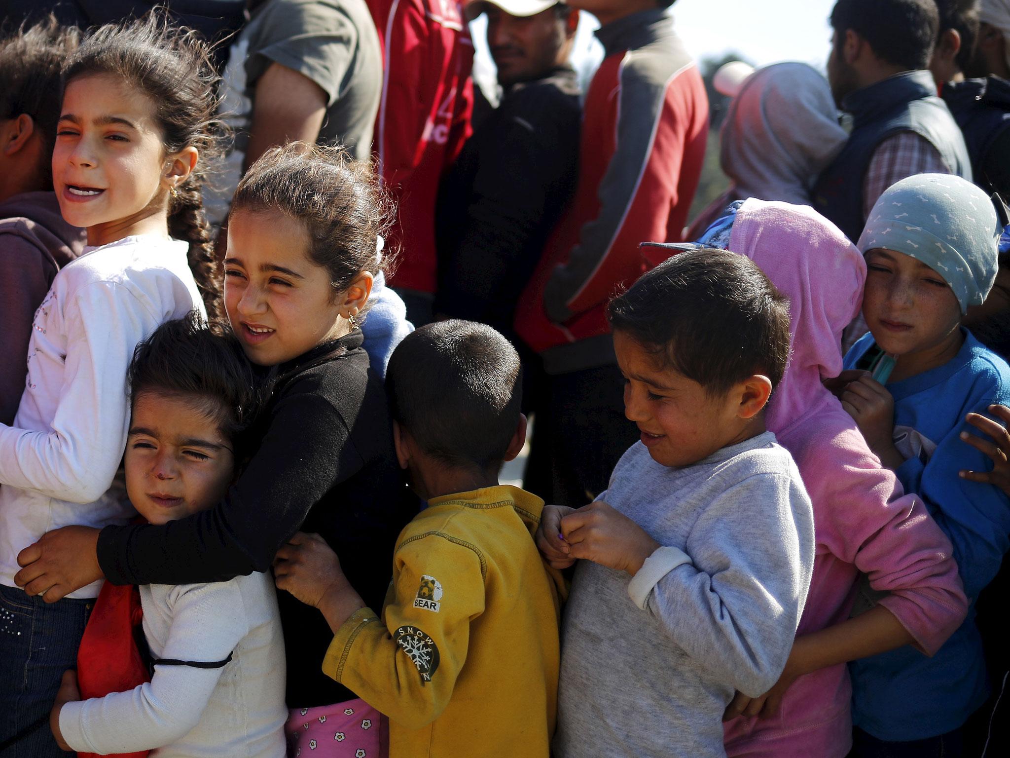 Children line up for food at a makeshift camp for refugees and migrants at the Greek-Macedonian border