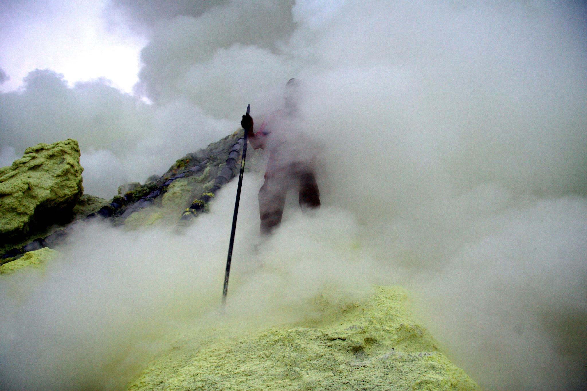An Indonesian sulphur miner collects sulphur from the crater atop the Ijen volcano in Banyuwangi, on East Java