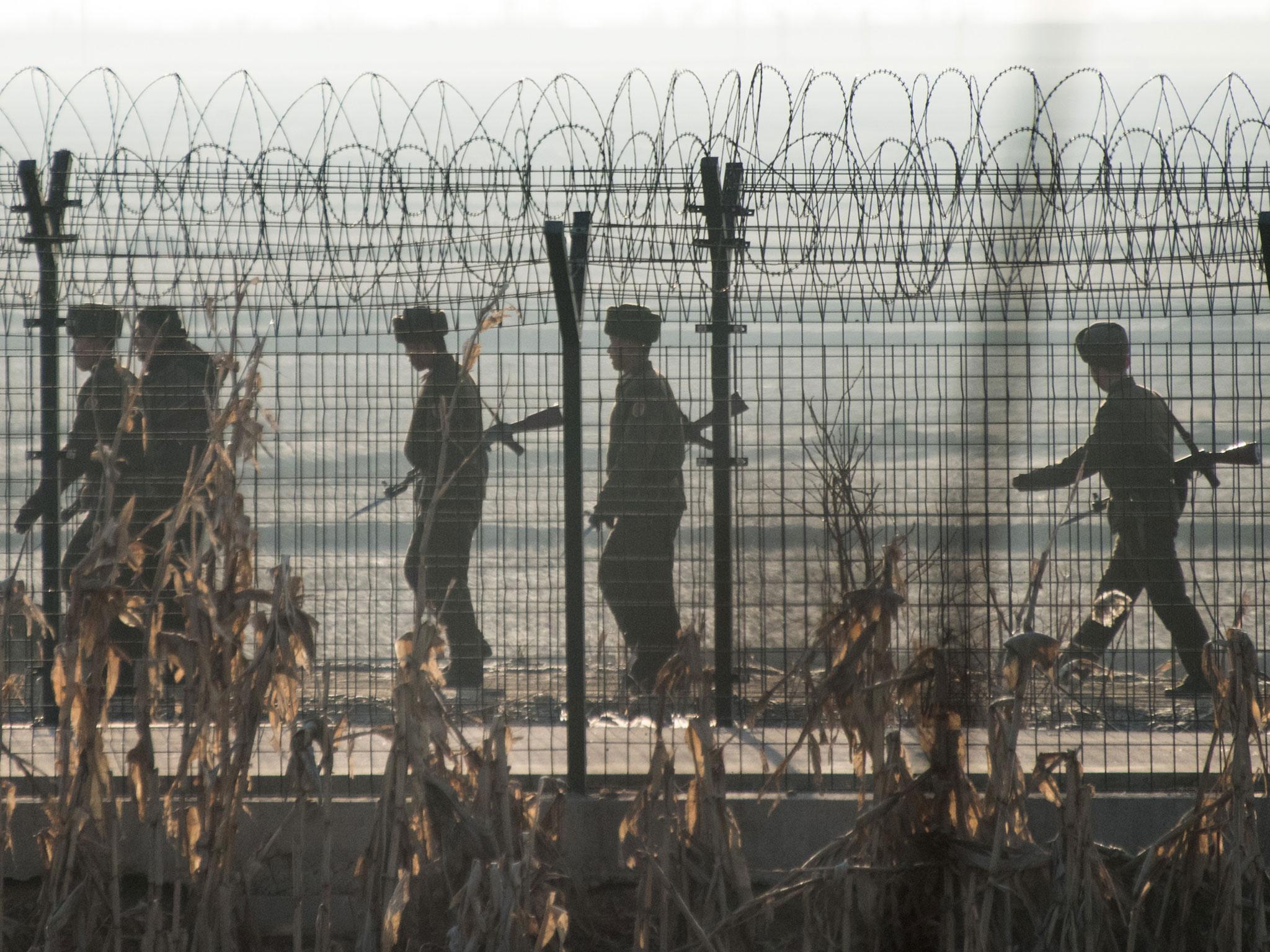 North Korean soldiers patrol next to the border fence near the town of Sinuiju across from the Chinese border town of Dandong on February 10, 2016