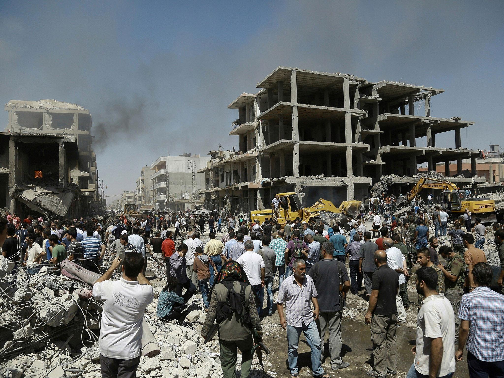 Syrians gather at the site of a bomb attack in Syria's northeastern city of Qamishli on 27 July, 2016