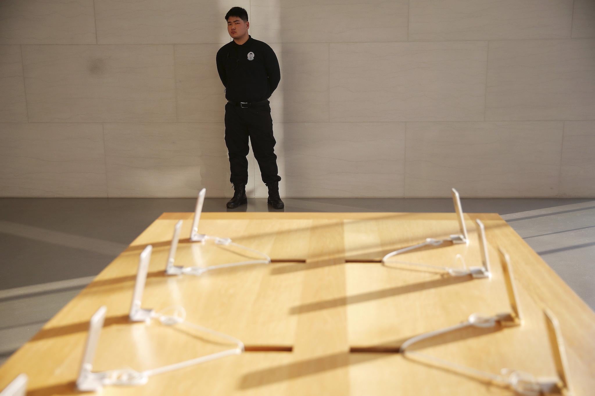 A security officer stands behind Apple iPhones displayed at an Apple store in Beijing, China, February 17, 2016
