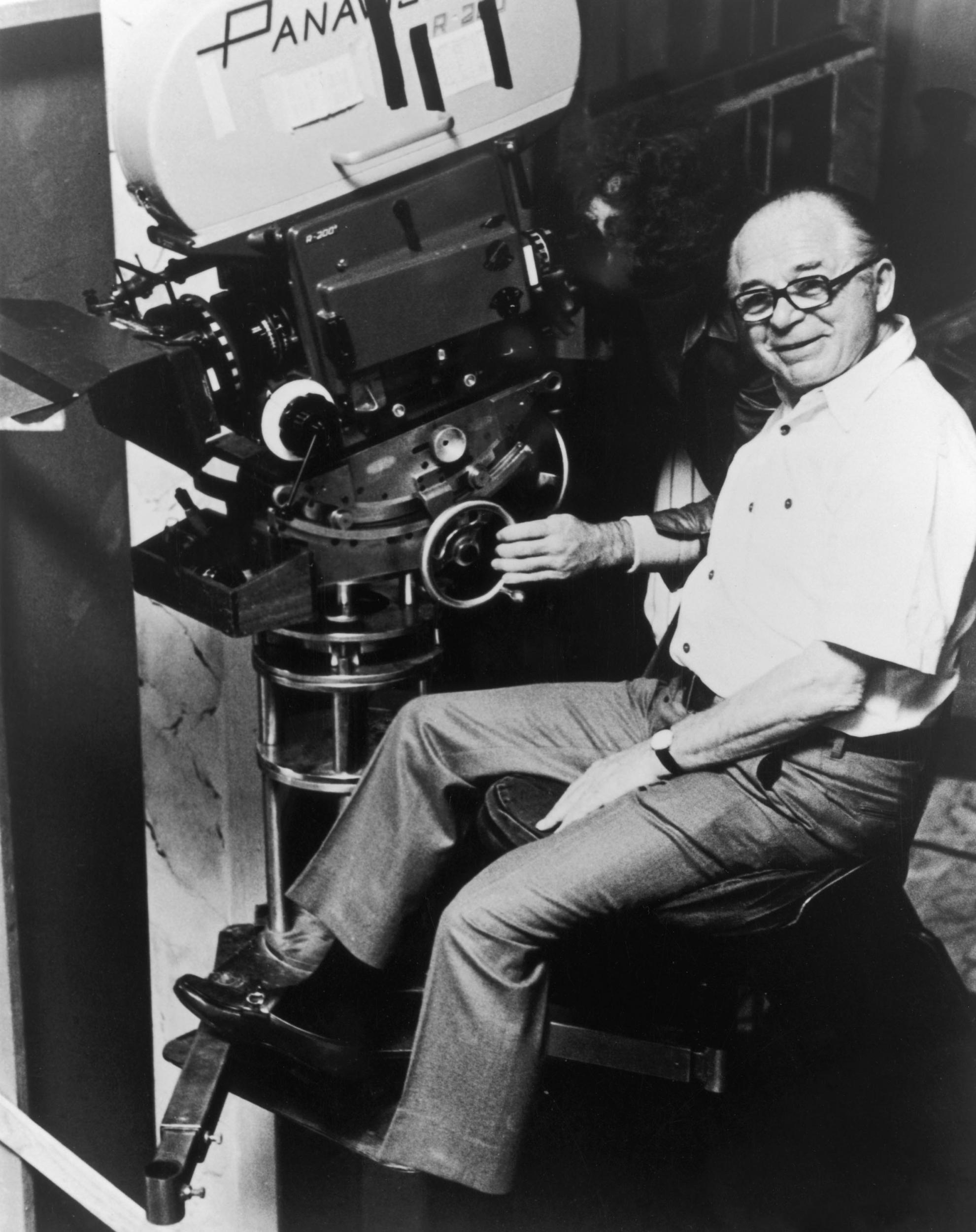 Director Billy Wilder smiles while sitting in front of a camera on the set of one of his films (Getty)