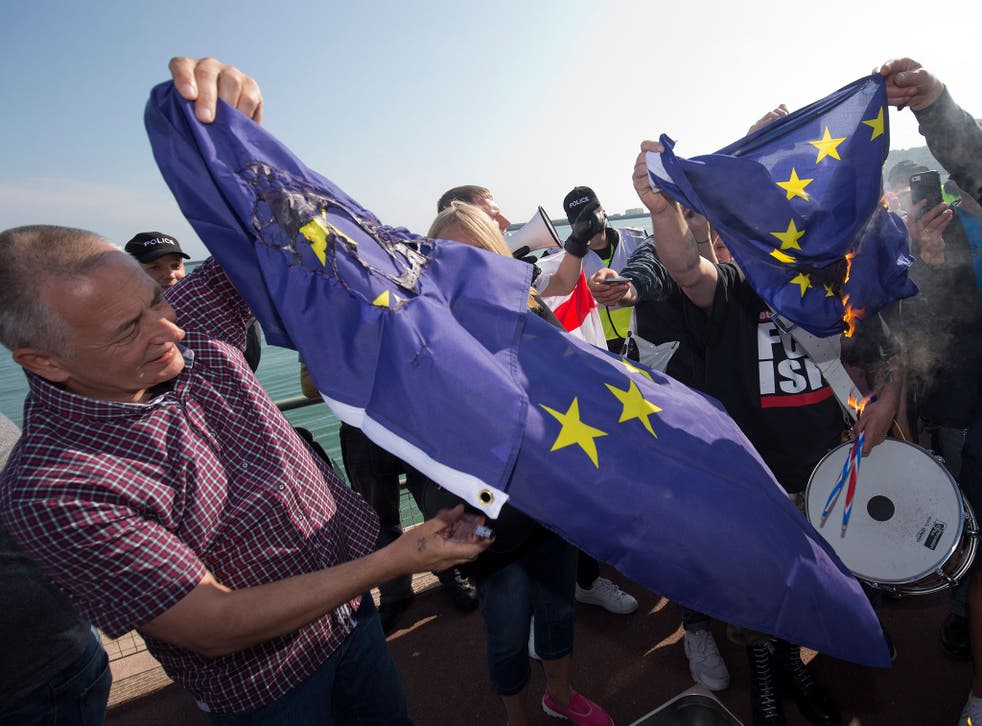 A group of far right protesters burn an EU flag after a demonstration through the town of Dover in south east England