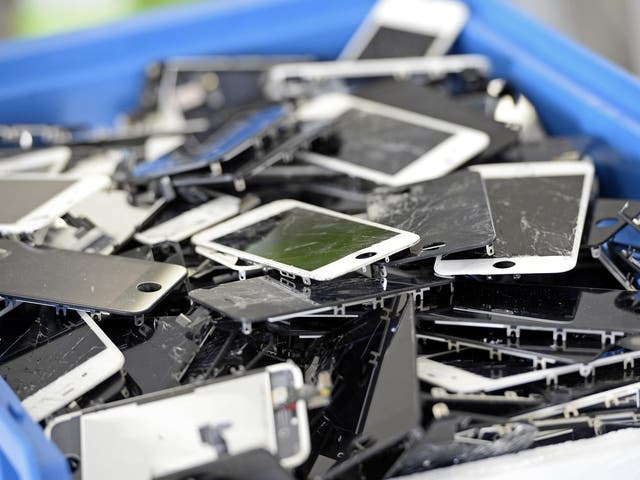 Damaged iPhones lie in a bin at Allo Smartphone’s Paris headquarters