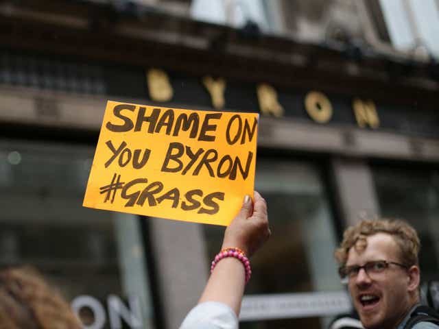 A woman holds up a sign outside a Byron restaurant in Holborn, central London, as people protest after dozens of workers at the burger chain were arrested in a swoop by immigration officials