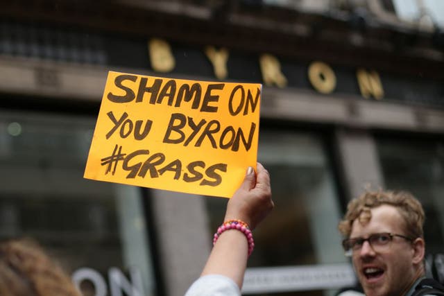A woman holds up a sign outside a Byron restaurant in Holborn, central London, as people protest after dozens of workers at the burger chain were arrested in a swoop by immigration officials