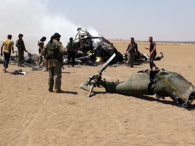 Syrian rebels gather around the wreckage of a Russian Mi-8 helicopter that was shot down on Monday