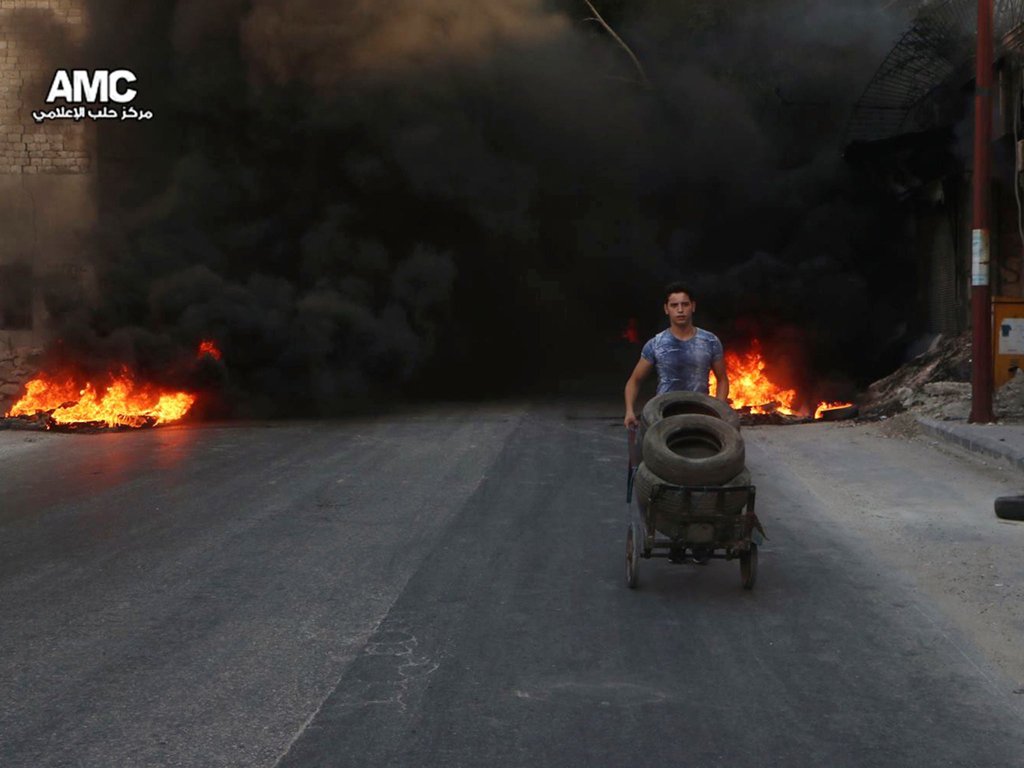 A Syrian man burns tyres in an attempt to prevent air strikes above Aleppo
