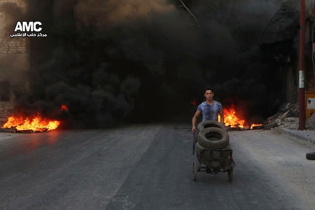 A Syrian man burns tyres in an attempt to prevent air strikes above Aleppo