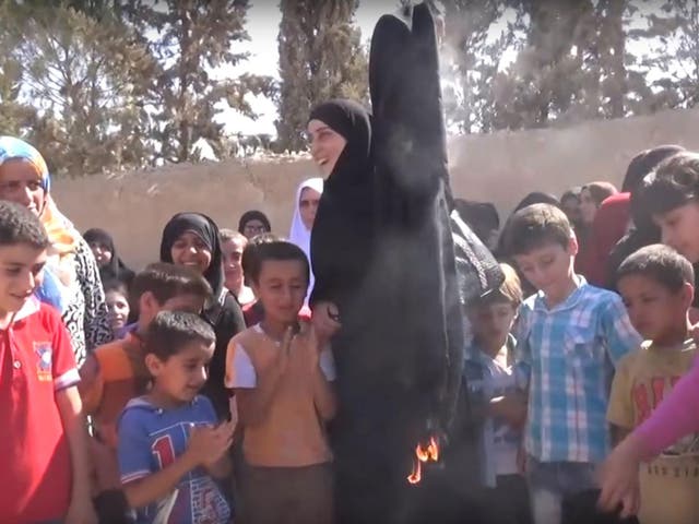Women burning the burqas Isis forced them to wear after militants were forced out of part of Manbij on 30 July