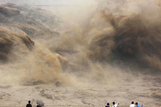 Visitors watch giant gushes of water released from the Xiaolangdi dam clearing up the sediment-laden Yellow river