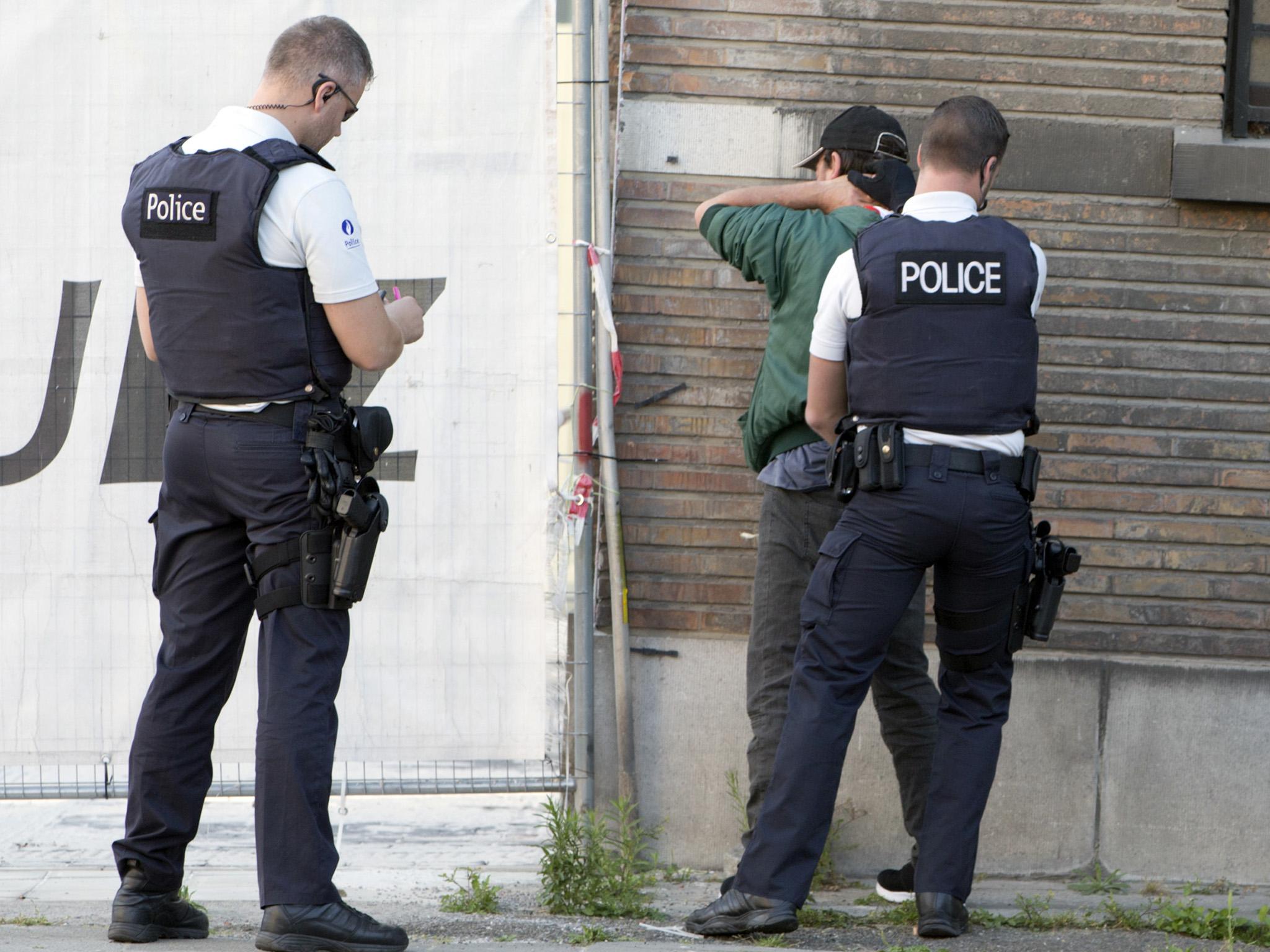 Police officers check identification of a man near the police headquarters in Charleroi