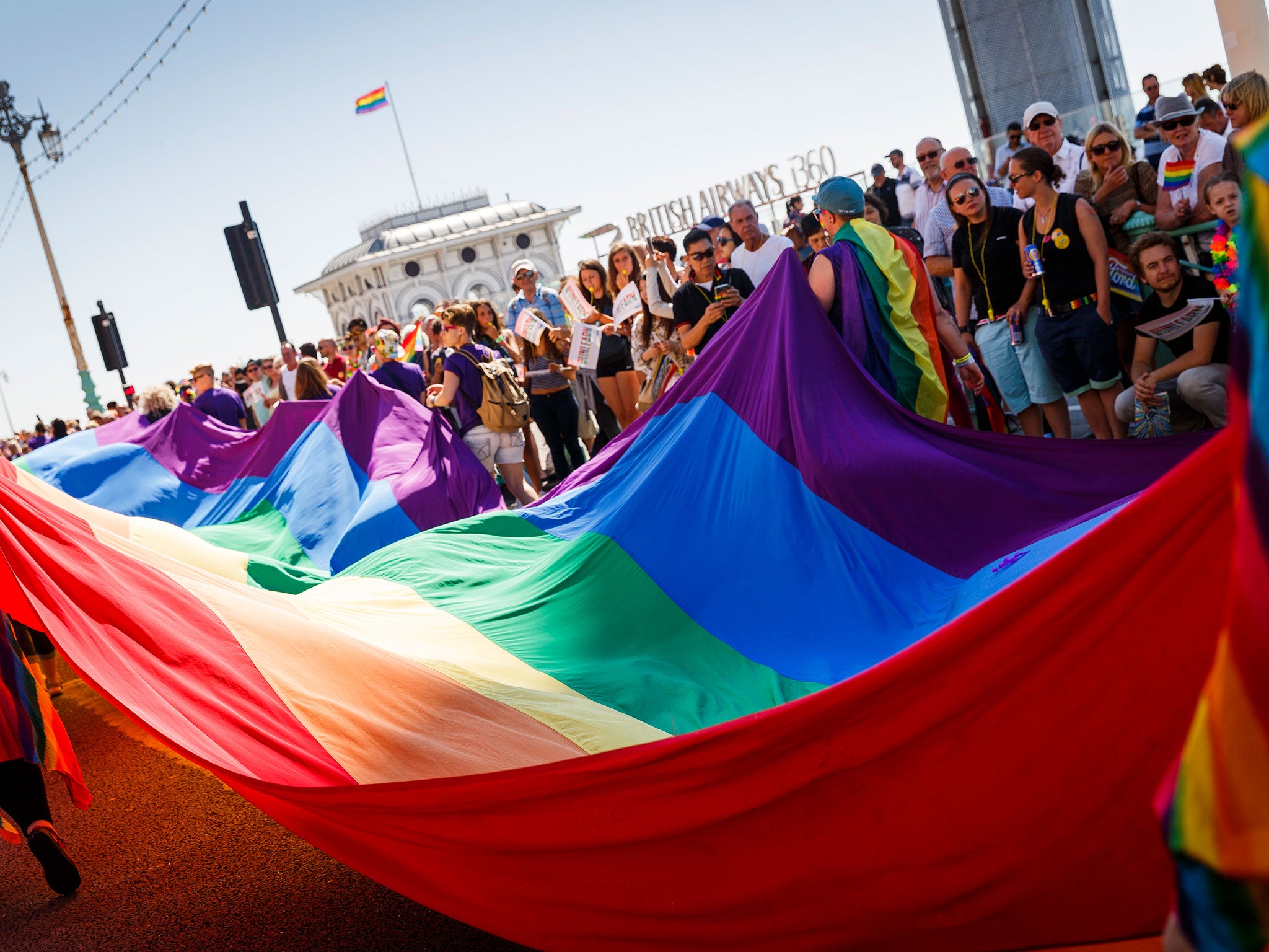 An enormous rainbow flag is paraded through crowds at Brighton Pride