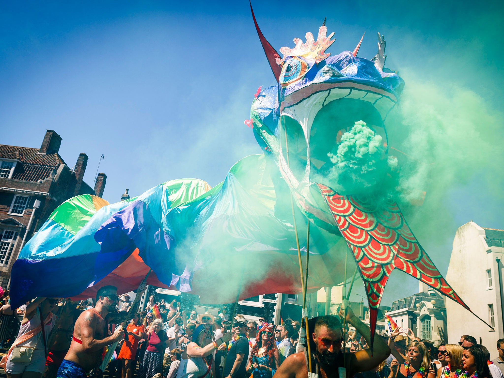 A dragon float, clad in rainbow silk, spews green smoke in a colourful display at Brighton Pride