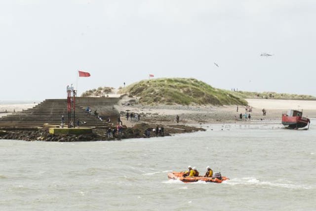 A RNLI lifeboat and a rescue helicopter search Barmouth Beach where two boys are missing in the sea