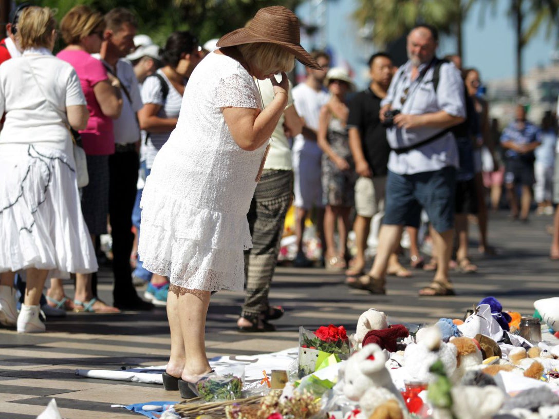 A woman dressed in white stands in front of the make shift memorial in tribute to the victims of the Bastille Day attack