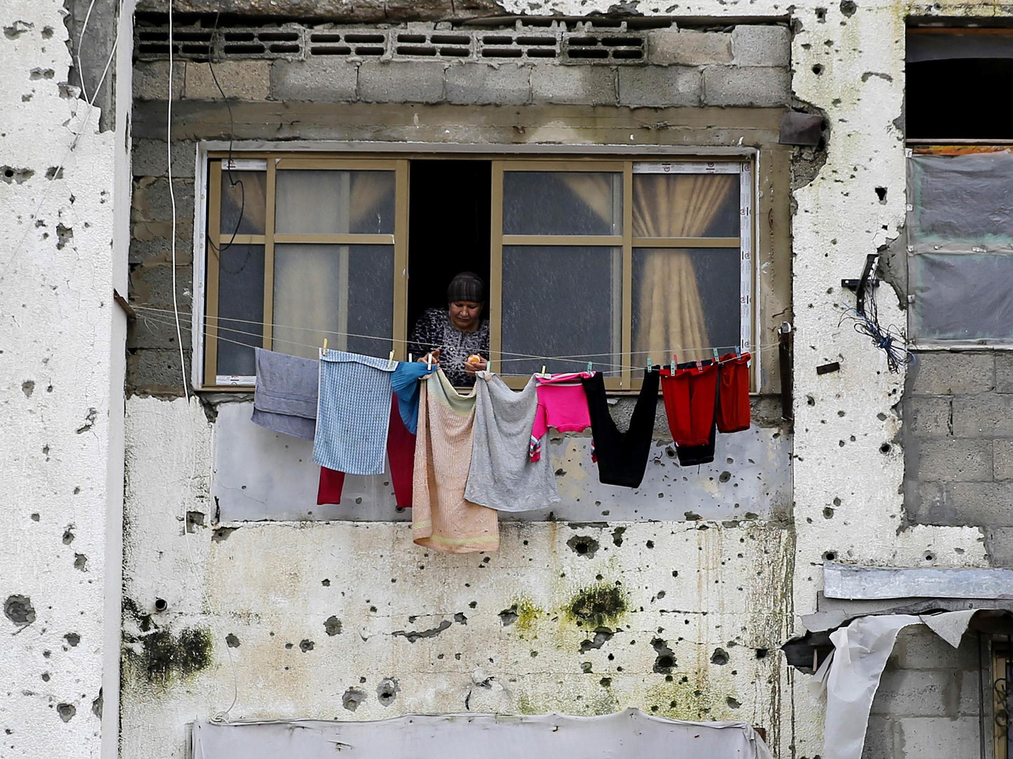 A Palestinian woman hangs clothes in a section of a damaged apartment block in Beit Lahiya, Gaza Strip