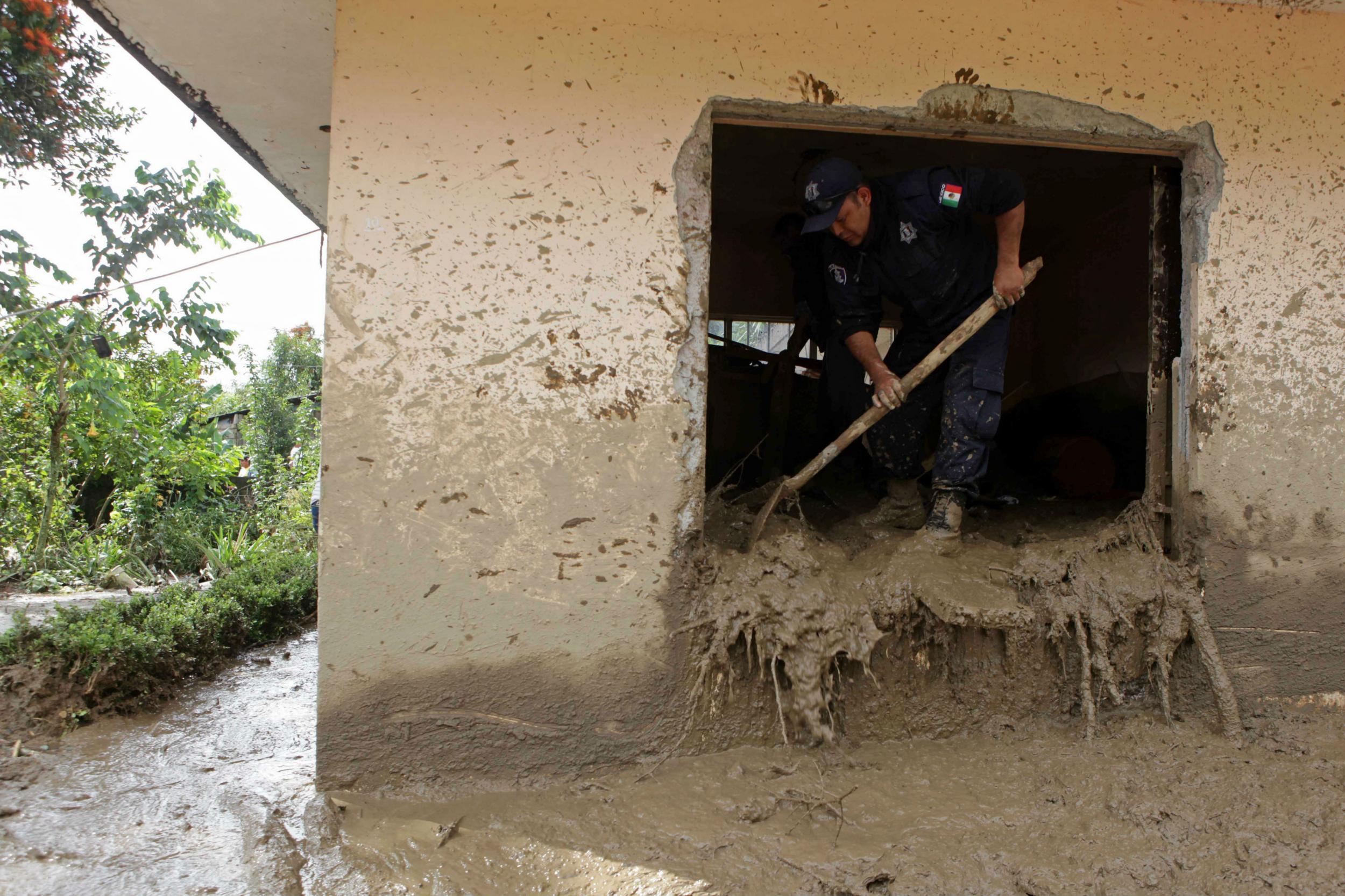 A federal agent helps clear mud from a house stricken by landslides and floods