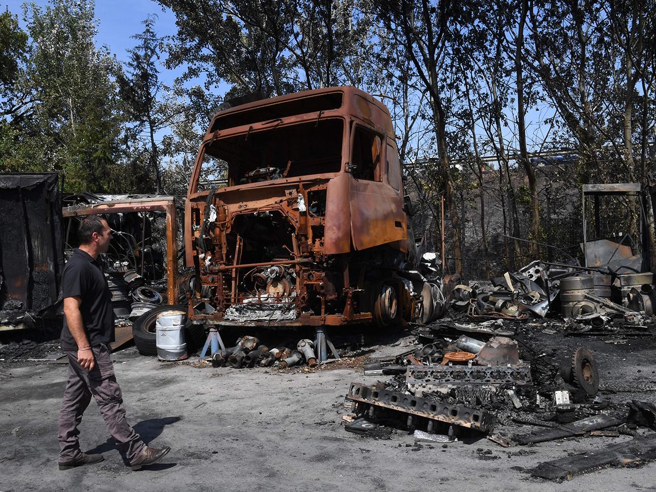 A man walks in front of burnt trucks following a fire which has devastated some 3,300 hectares in the area, in Les Pennes Mirabeau, north of Marseille on August 11, 2016