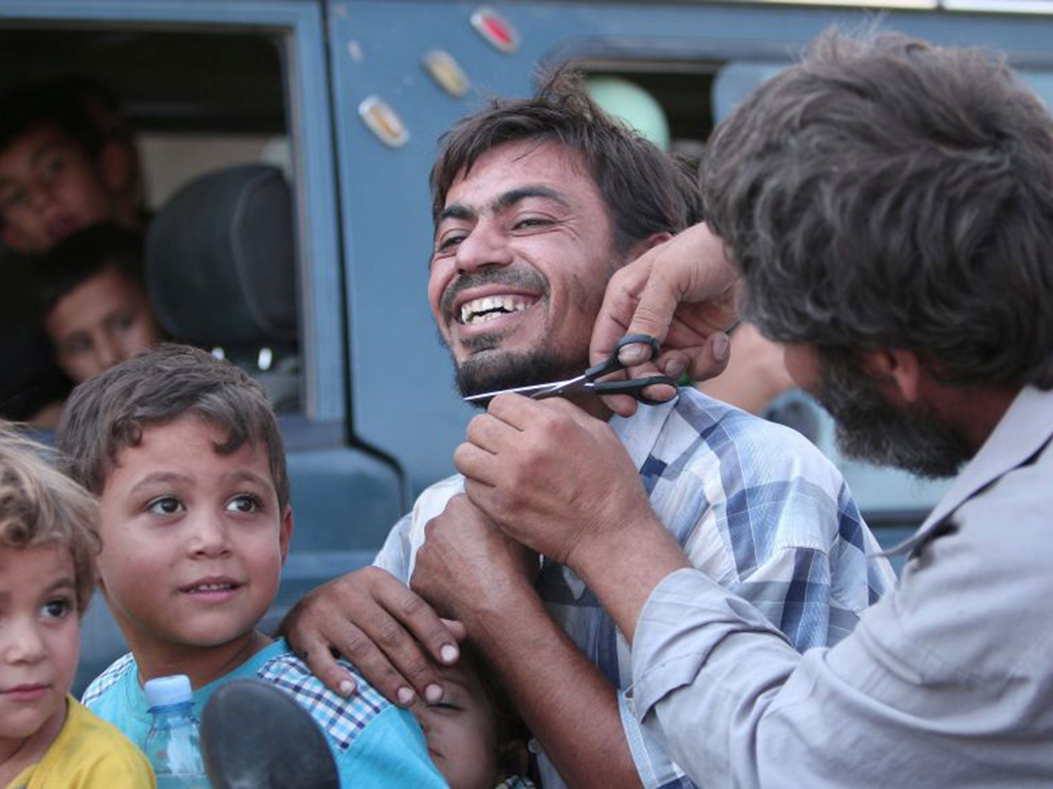 A man cuts the beard of a civilian who was freed from Isis by the SDF in Manbij on 12 August