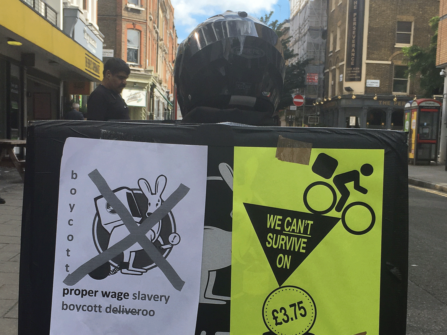 A striking Deliveroo worker protests against 'slavery' on their moped as the company seeks to impose a new contract