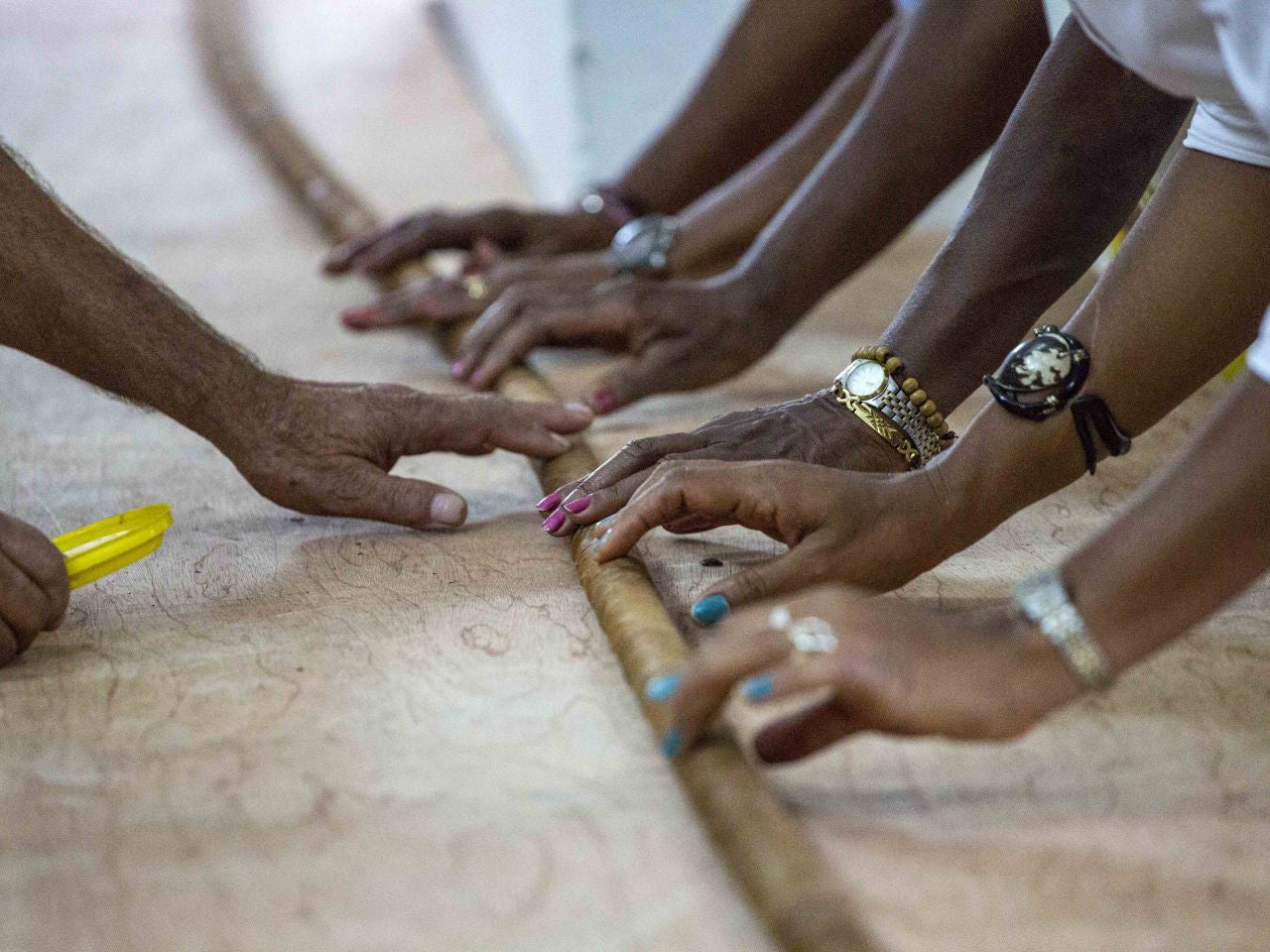 Workers help Cuban cigar roller Jose "Cueto" Castelar Hand roll a 90m cigar