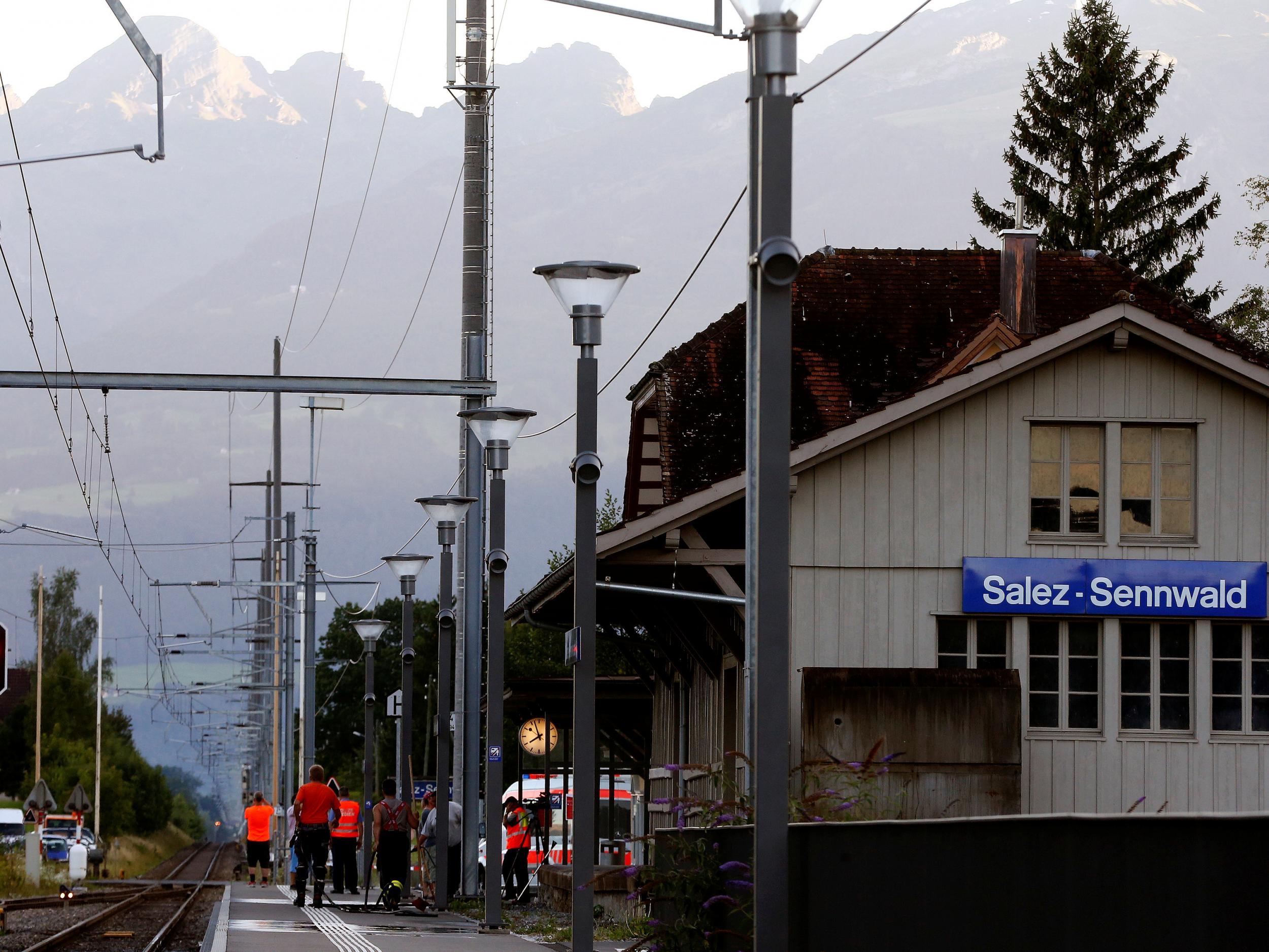 Workers clean a platform after an attack on a Swiss train at the railway station in the town of Salez