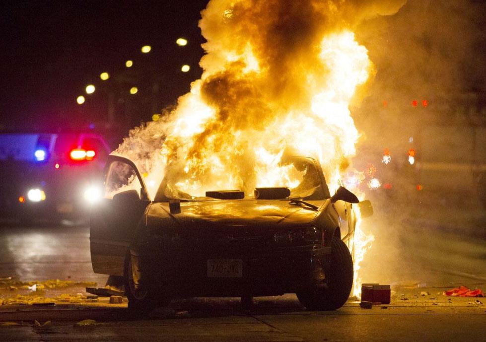 A car goes up in flames as more than 100 protesters gather following the fatal shooting of a man in Milwaukee