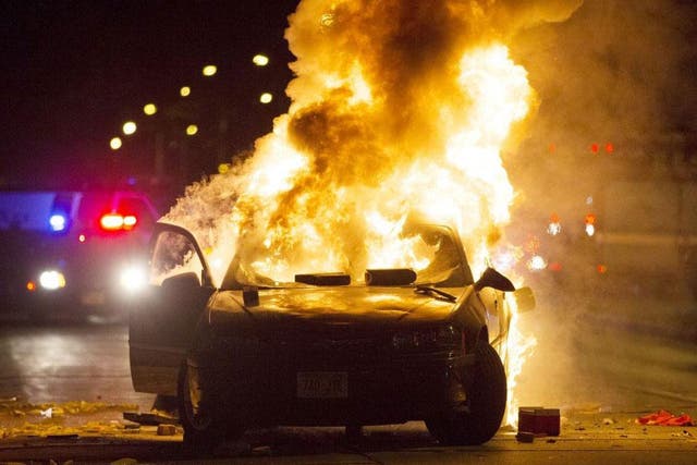A car goes up in flames as more than 100 protesters gather following the fatal shooting of a man in Milwaukee