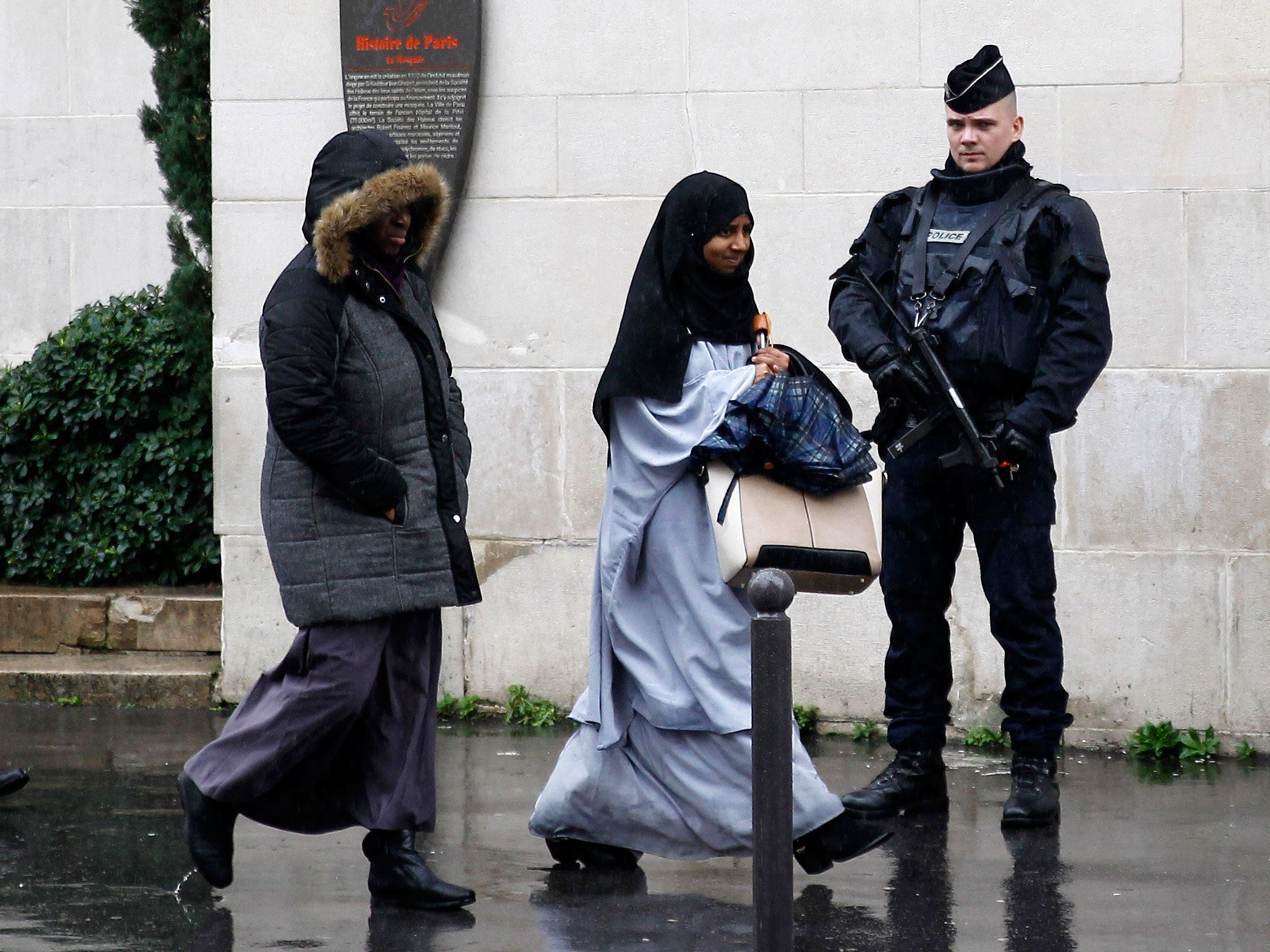 A French police officer stands guard as Muslim women leave the Great Mosque of Paris (Grande mosquee de Paris) after the Friday prayers on November 20, 2015 in Paris, France.