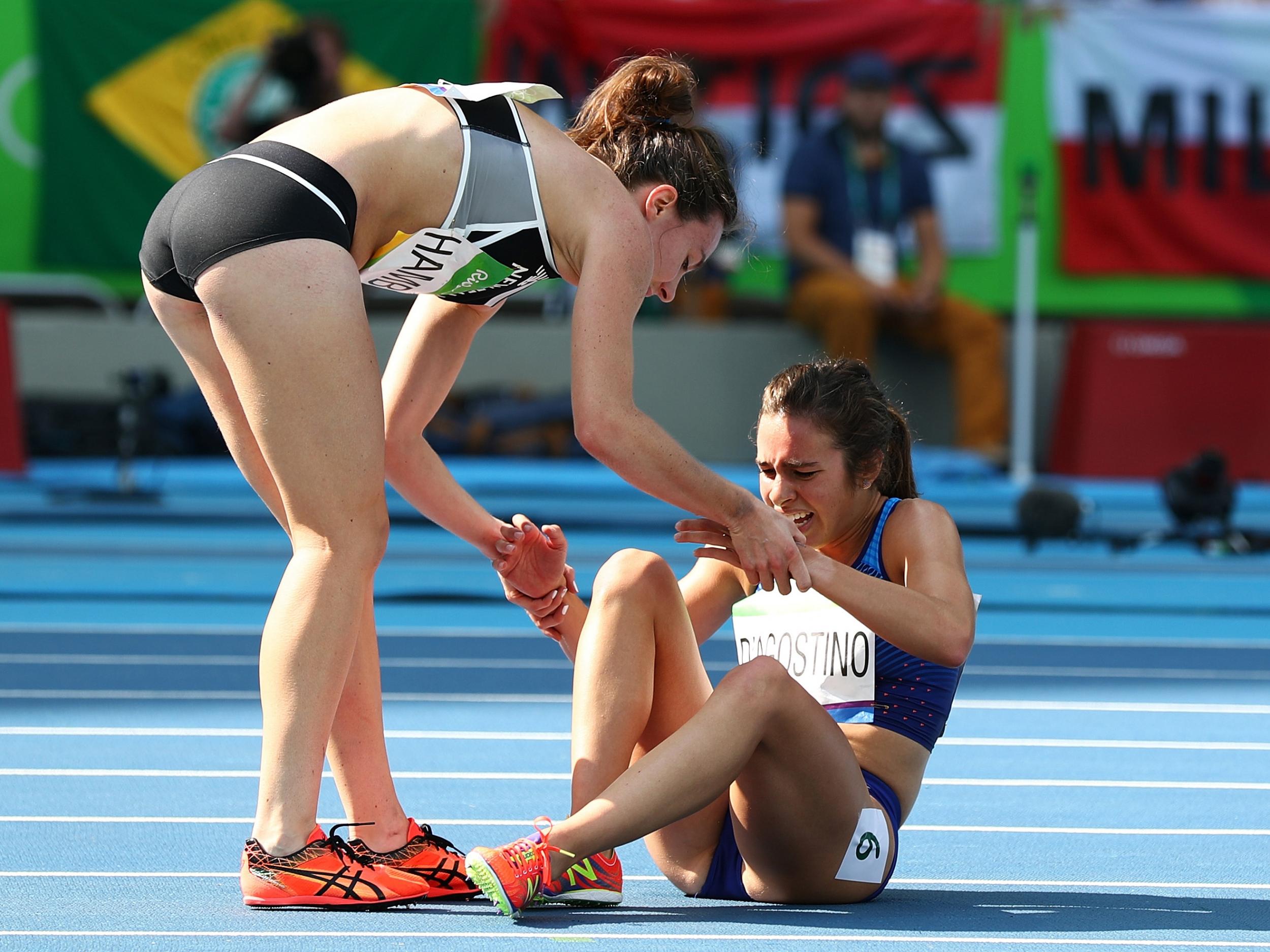 Abbey D'Agostino of the United States (R) is assisted by Nikki Hamblin of New Zealand after a collision during the Women's 5000m Round 1